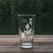 Load image into Gallery viewer, A clear glass tumbler with a printed design of a lake on it, placed on a wooden surface.
