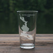 Load image into Gallery viewer, A clear glass with a white map of Mooselookmeguntic Lake printed on it, sitting on a wooden surface.
